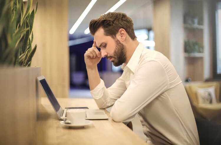 Canva   Man With Hand On Temple Looking At Laptop (3)